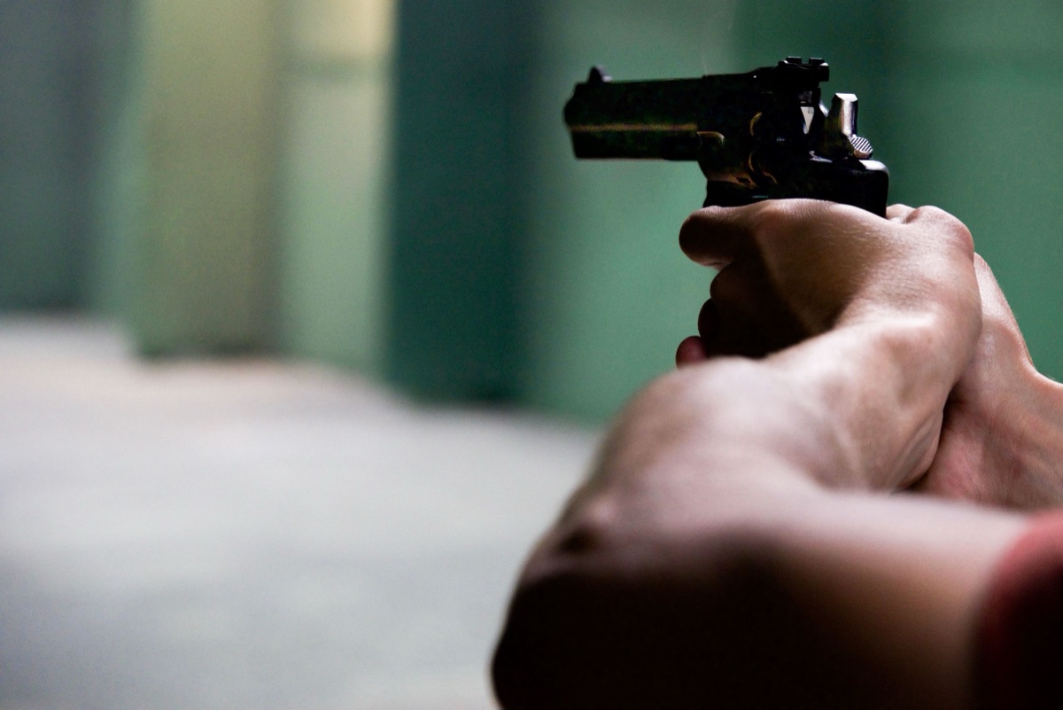 Two hands on a hammer-fired pistol at the range — the same grip that felt solid on a GBB has to hold a live 9mm still
