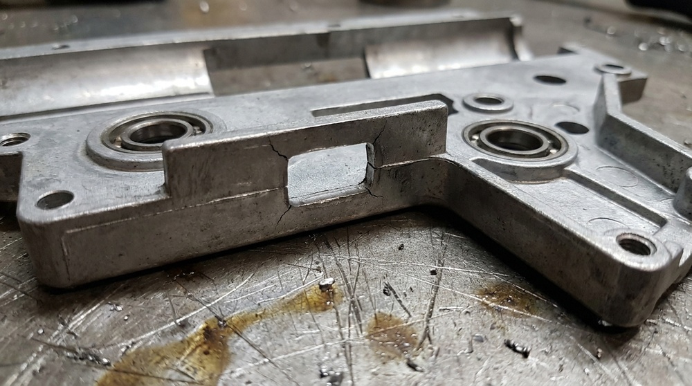 A bare version 2 gearbox shell half with hairline cracks running from the corners of the cylinder window