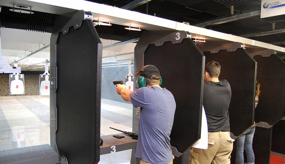 Shooters working adjacent lanes at an indoor pistol range