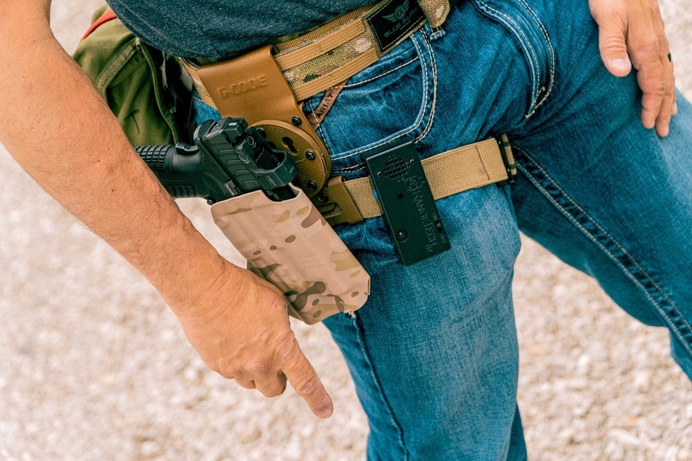 Shot timer clipped to a shooter’s belt next to a holstered pistol