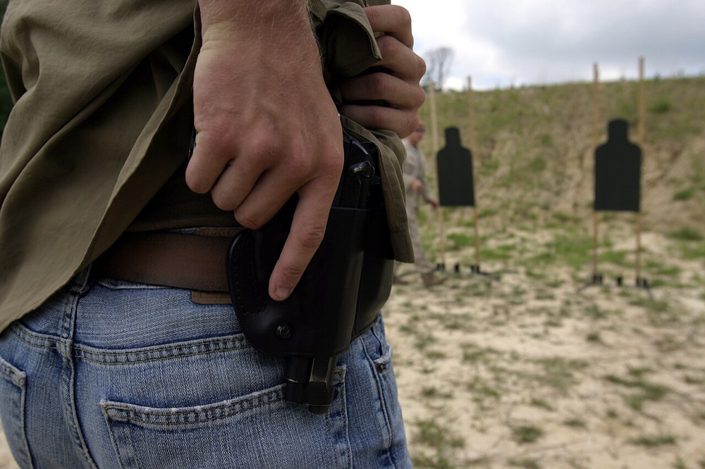 Shooter gripping a holstered pistol under a cover garment before the draw