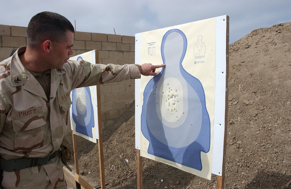 Instructor pointing at a group of hits on a silhouette qualification target