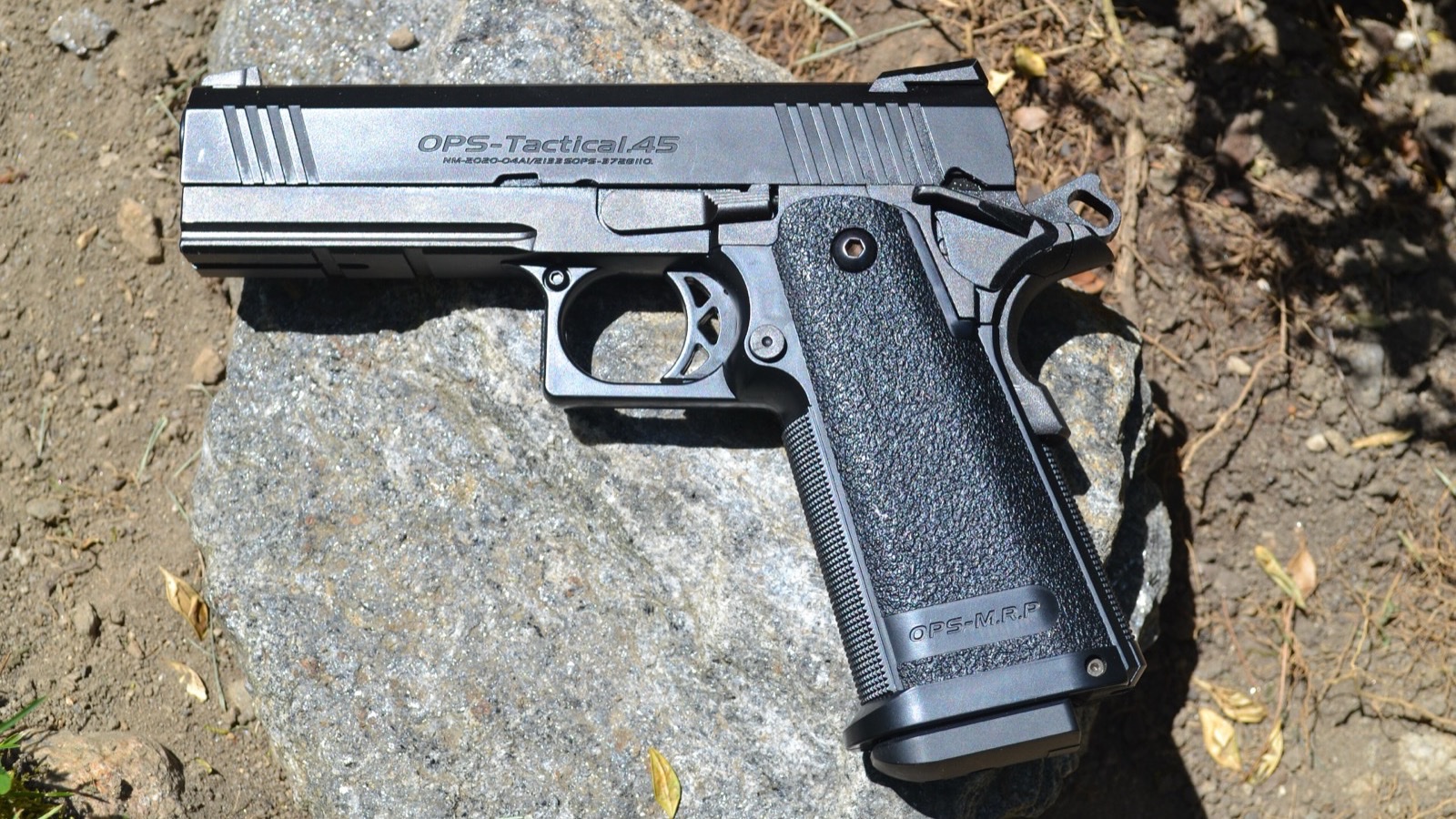 A Tokyo Marui Hi-CAPA 4.3 gas blowback airsoft pistol resting on a granite rock in sunlight