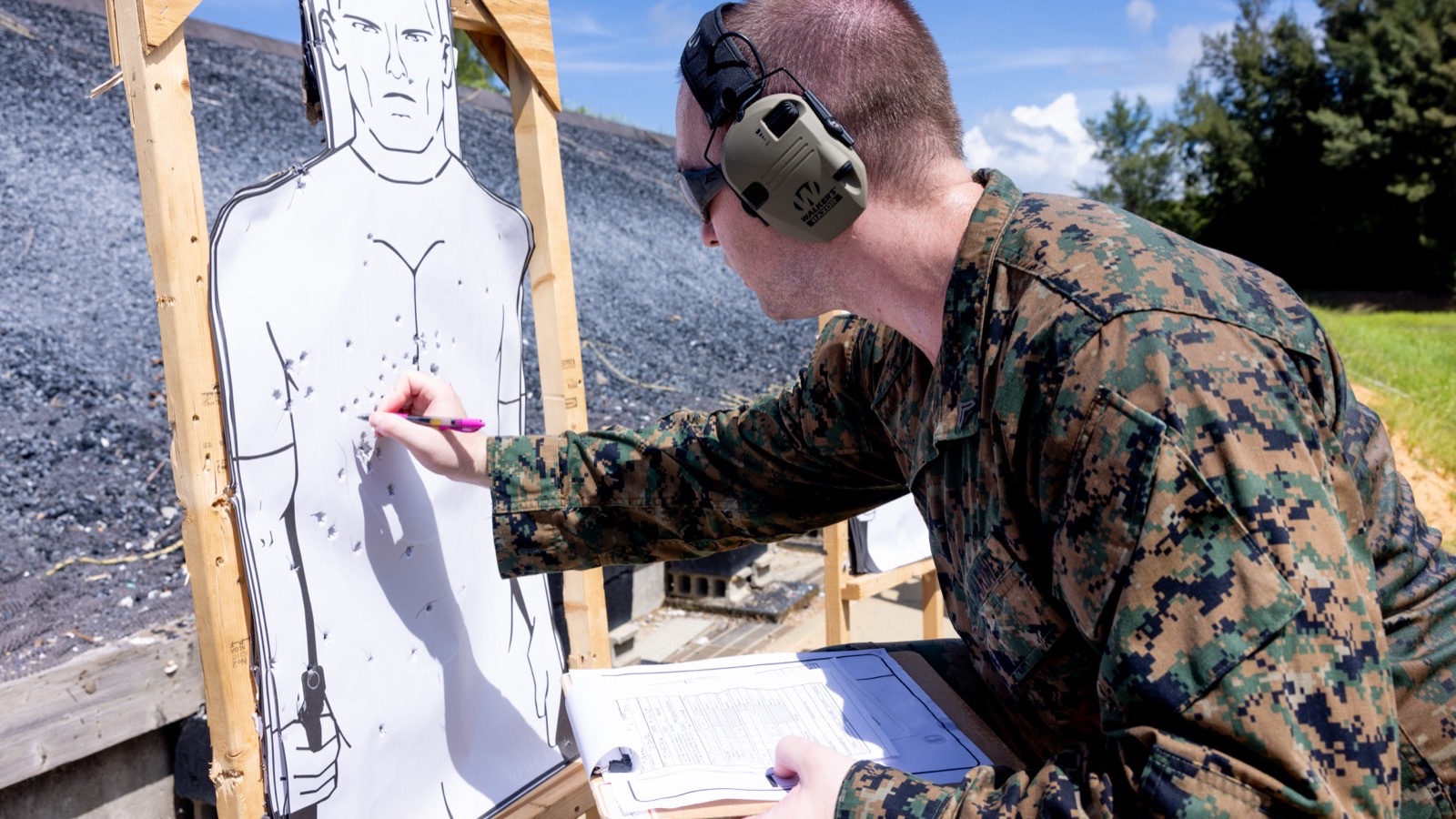 陸戰隊員在 Combat Pistol Program 考核中拿著計分表標記人形靶上的彈孔