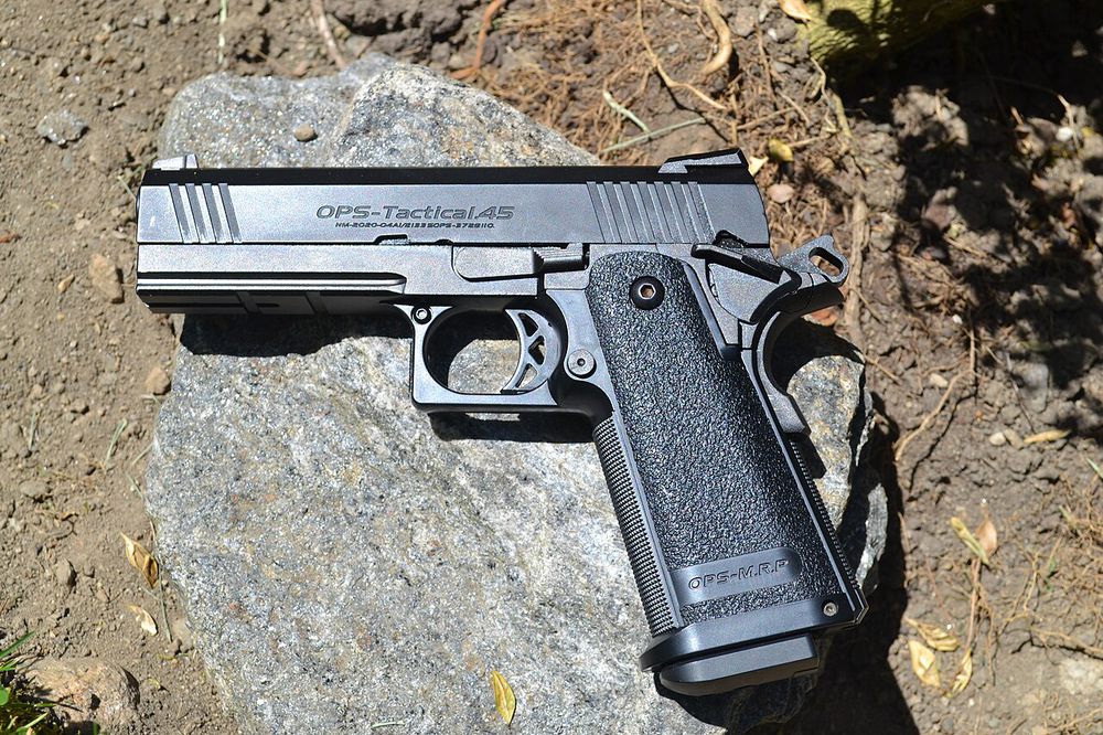 Tokyo Marui Hi-Capa 4.3 gas blowback airsoft pistol resting on a rock