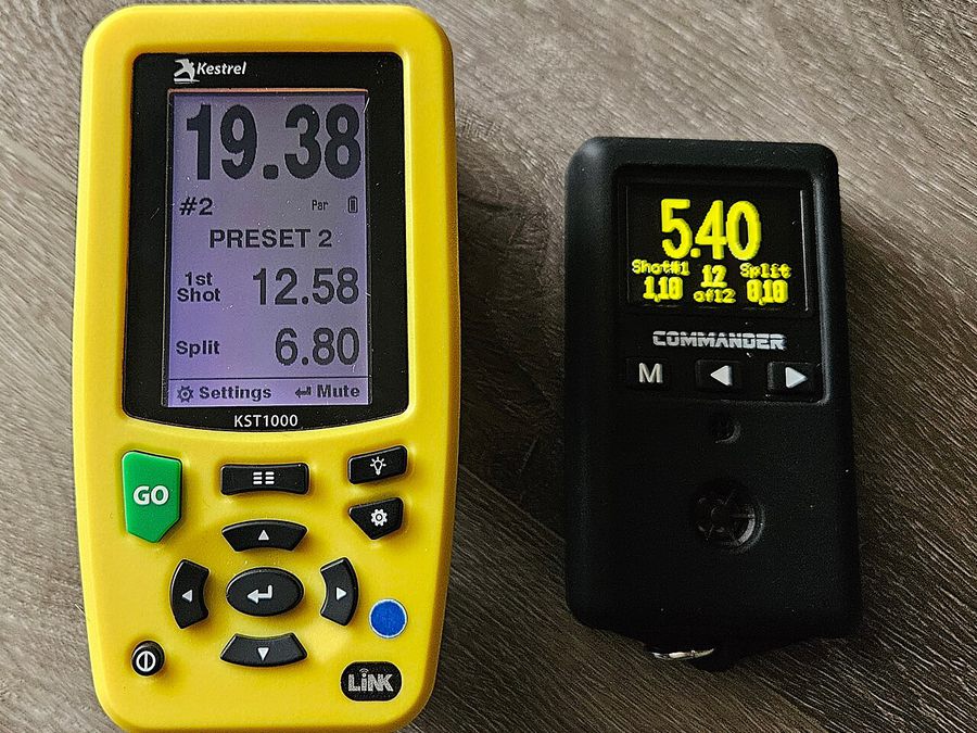 Two dedicated shot timers side by side on a wooden table