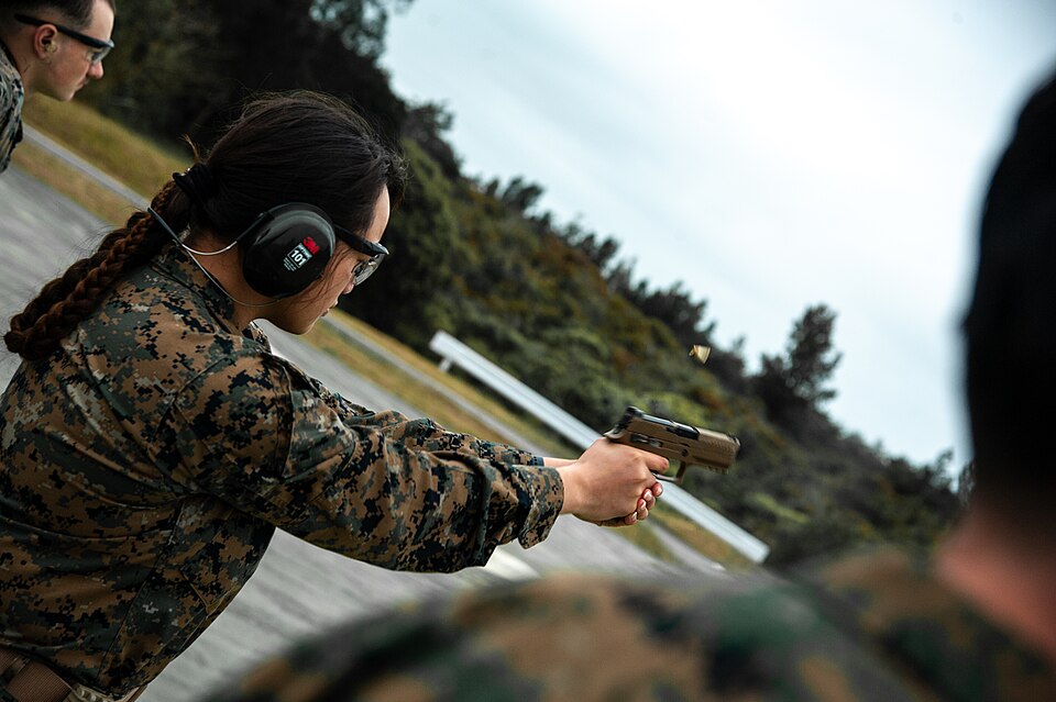 射手在實彈靶場上以雙手握把、雙臂完全前伸的姿勢，雙眼張開、視線穿過手槍瞄具對準目標