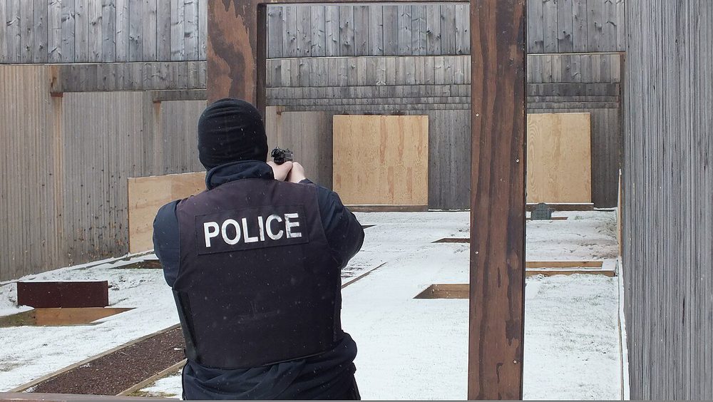 穿防彈背心的警察在資格射擊場上正身持槍，雙臂伸直成等腰式